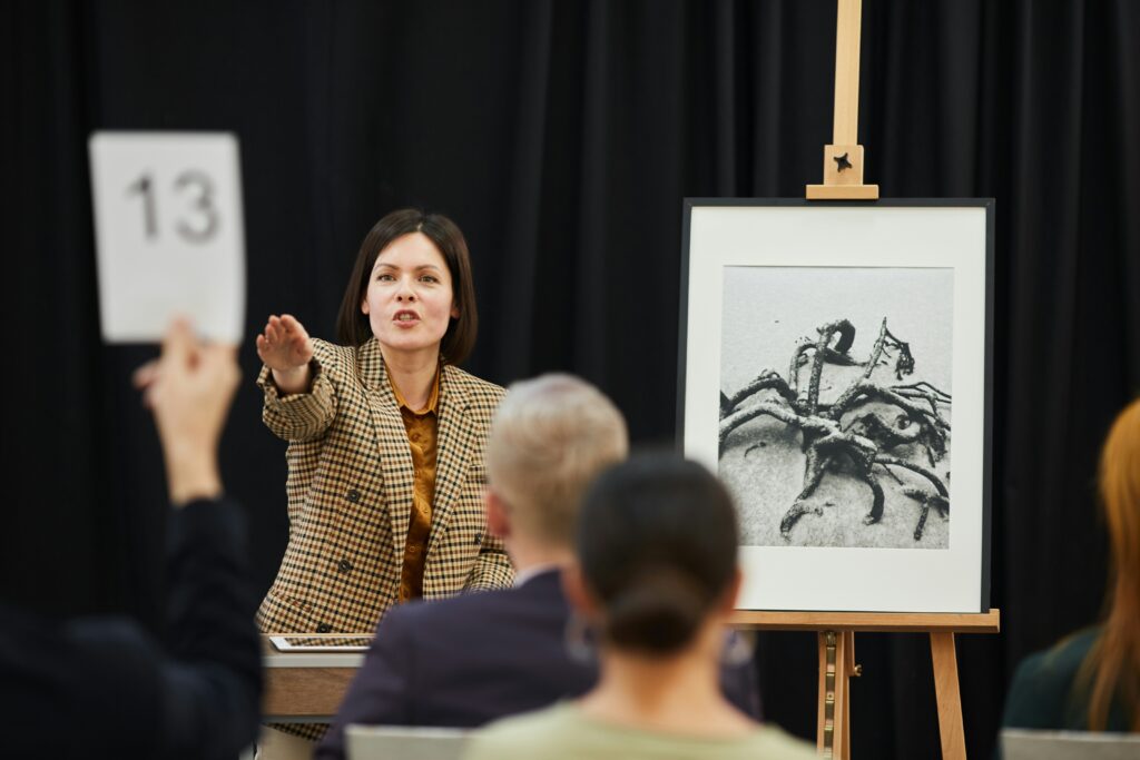 Auction house bidding paddle raised at a live sale — representing fine art auction advertising