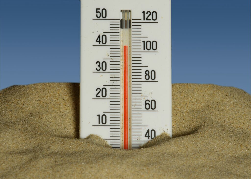 A thermometer reading high temperatures in sand against a blue sky, representing the UK heatwave