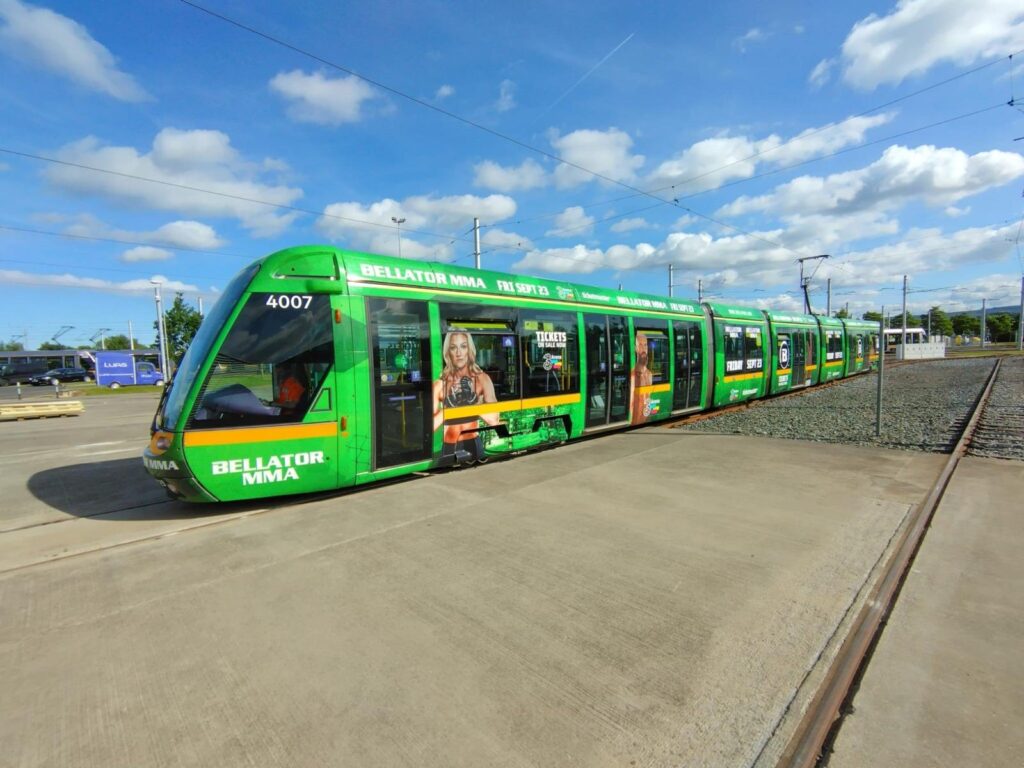 Green Luas tram in Dublin fully wrapped with Bellator MMA advertising, an example of transport advertising
