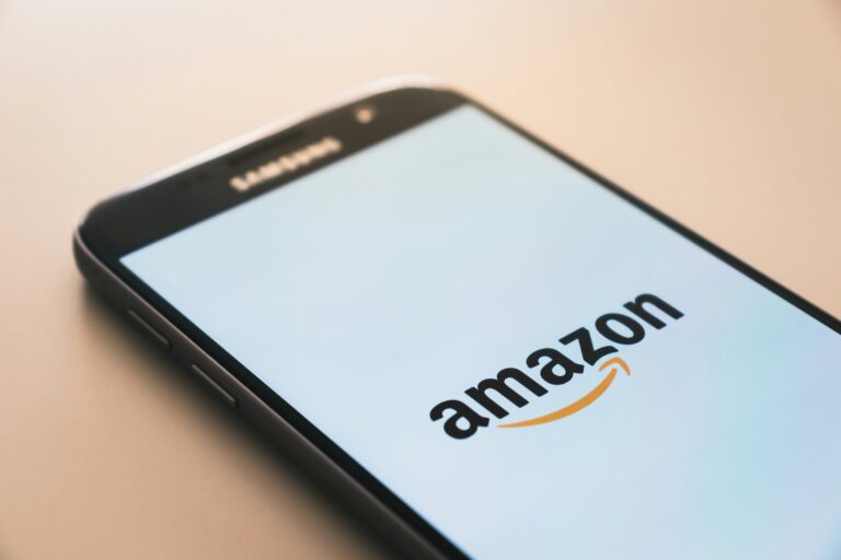 Samsung smartphone on a peach surface showing the Amazon logo on its screen
